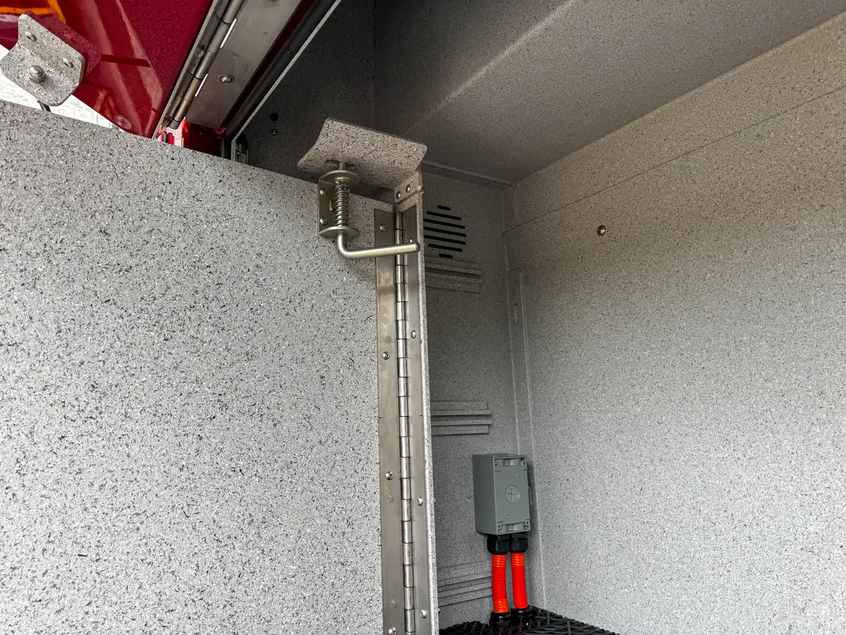 Side body detail near rear wheel showing marker light and utility fittings.